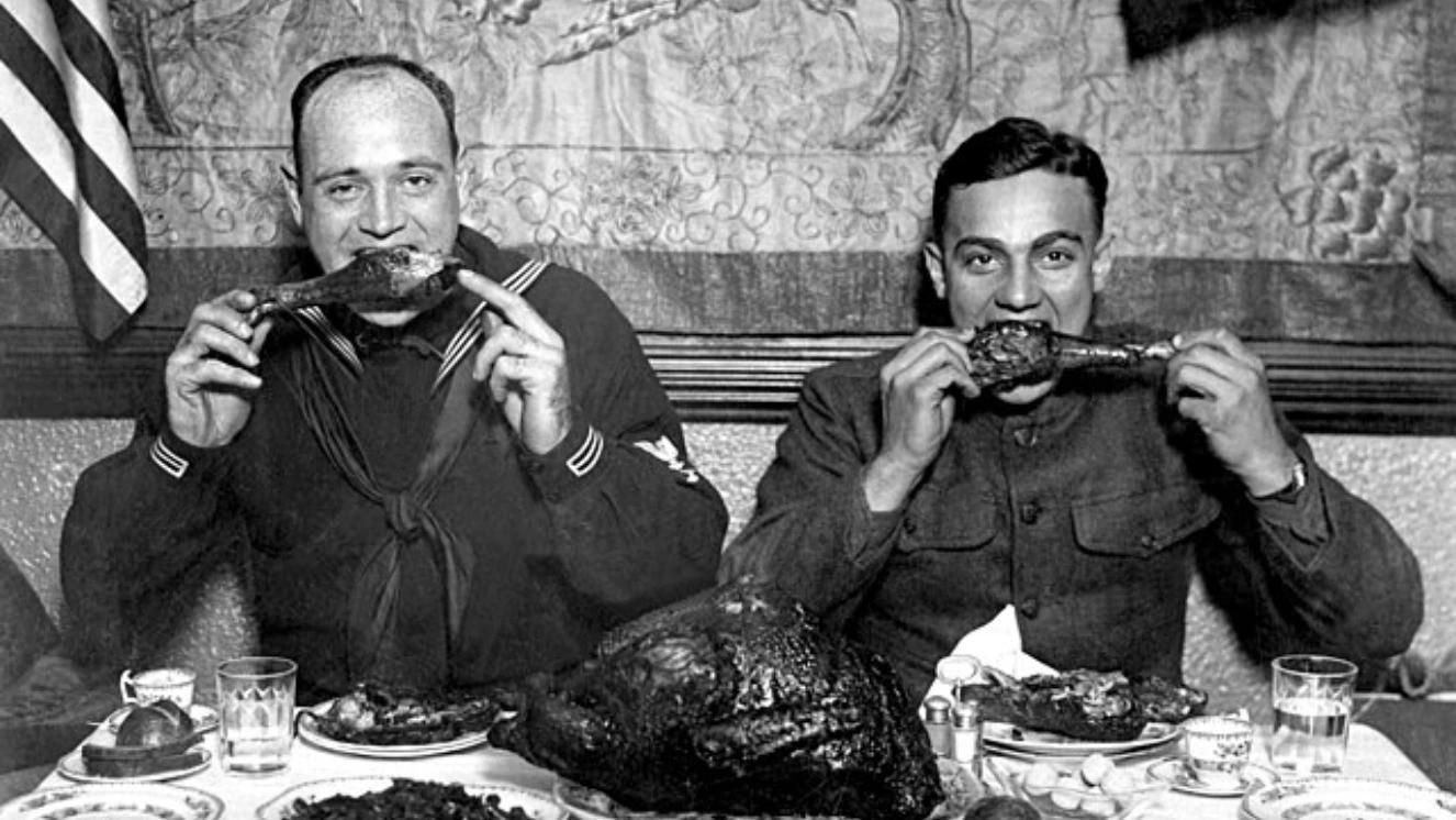 Sailor and soldier enjoying Thanksgiving meal with turkey in World War 2 setting