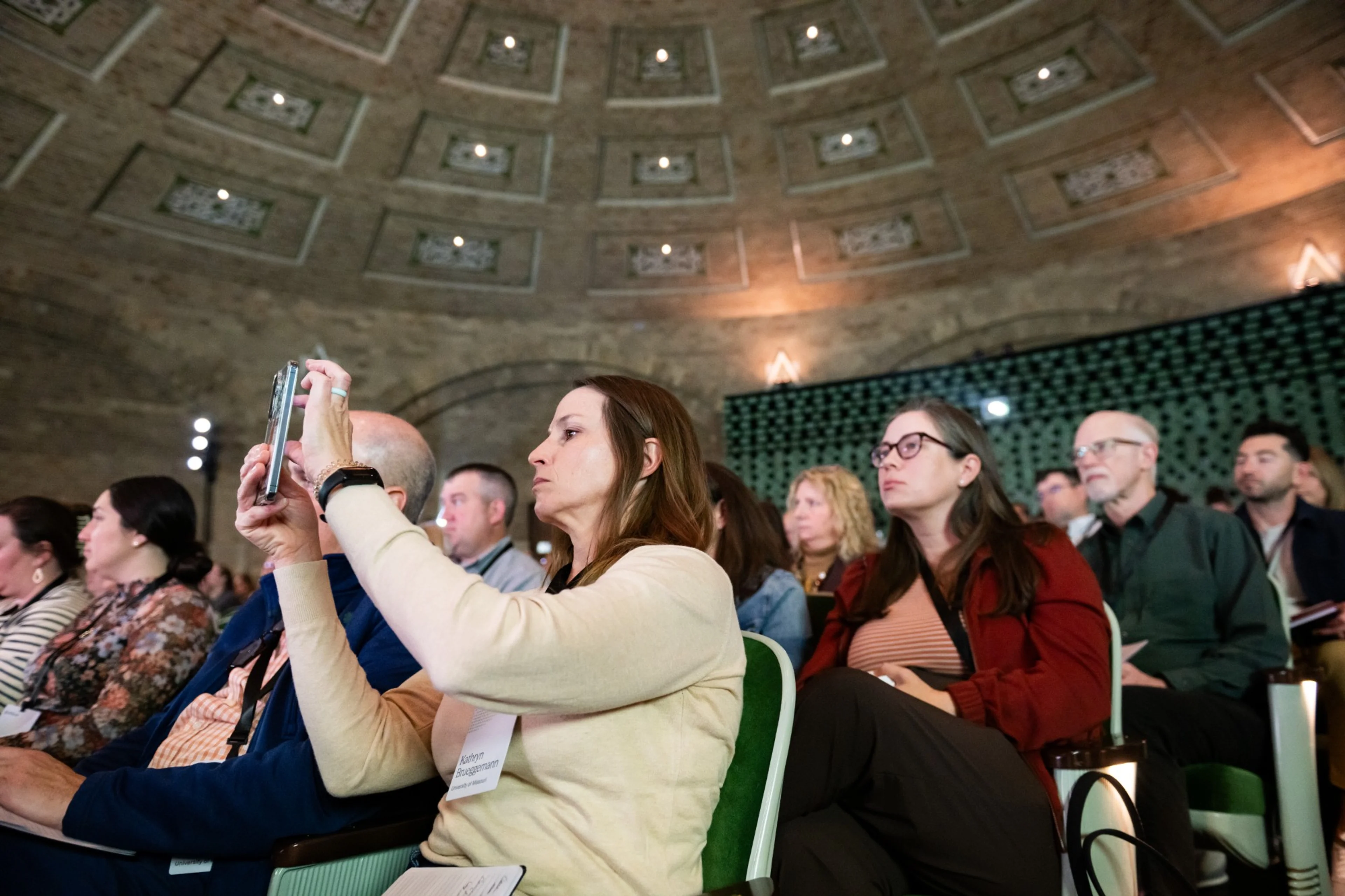 An attendee photographing a finalist presentation at Stellic Summit