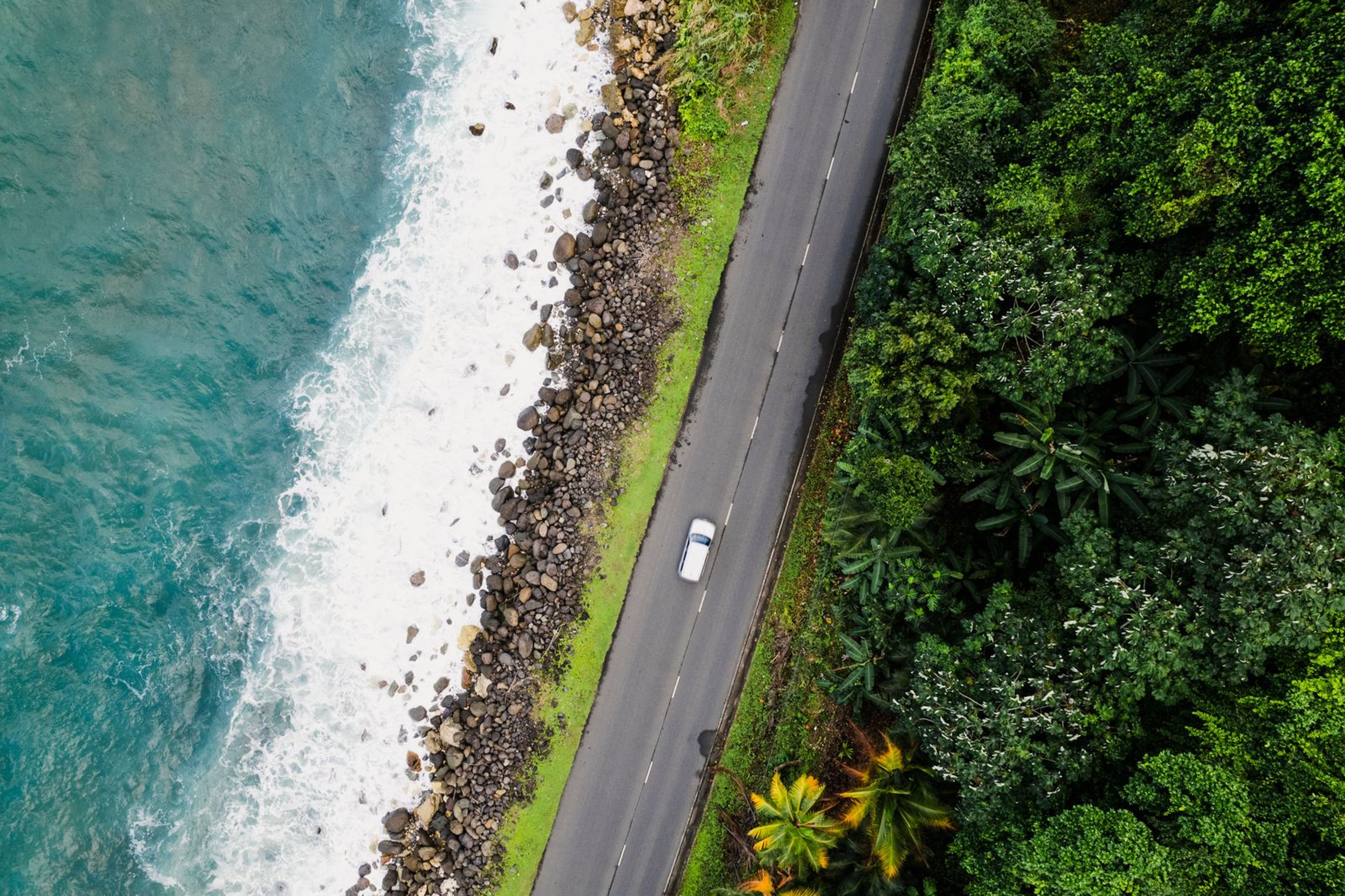 Vue aérienne d’une voiture sur une route côtière sinueuse