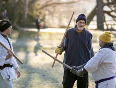 Instructor teaching bokken wooden sword techniques to students at outdoor aikido seminar