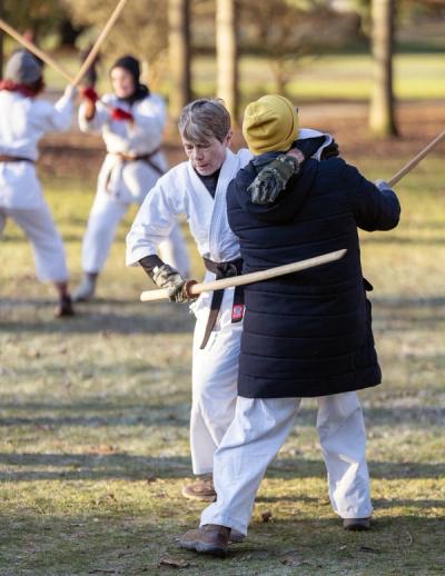 Two aikido practitioners practicing jo technique during outdoor winter training
