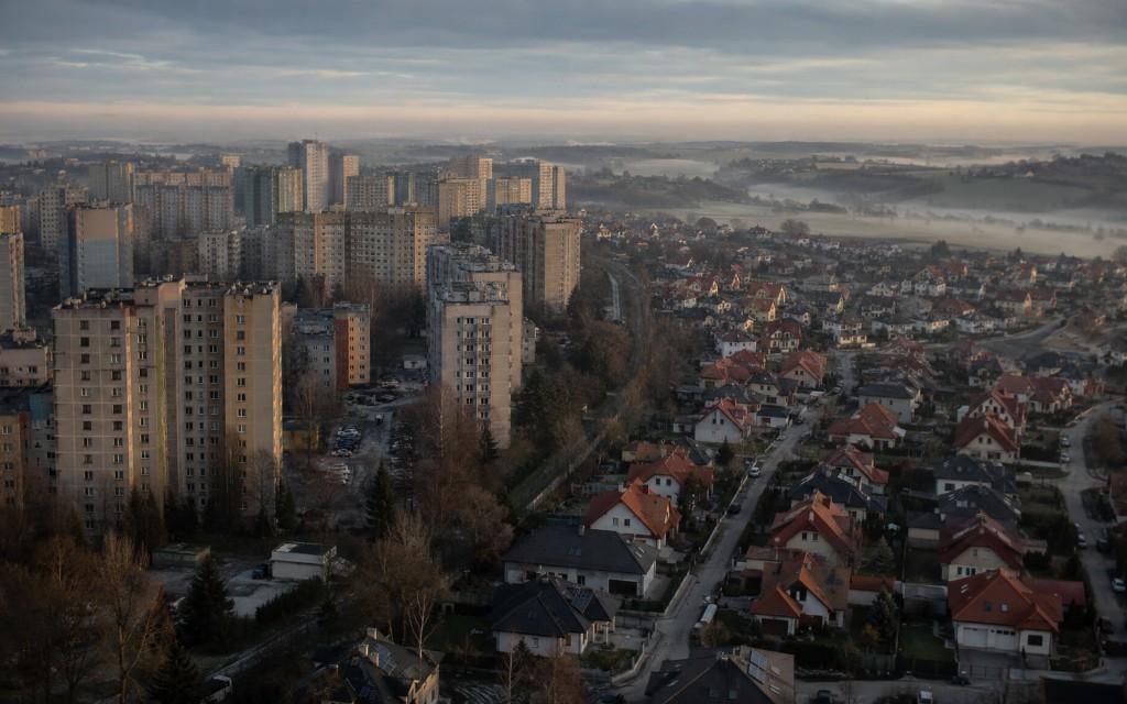 Stare bloki mieszkaniowe obok nowej zabudowy jednorodzinnej na obrzeżach miasta