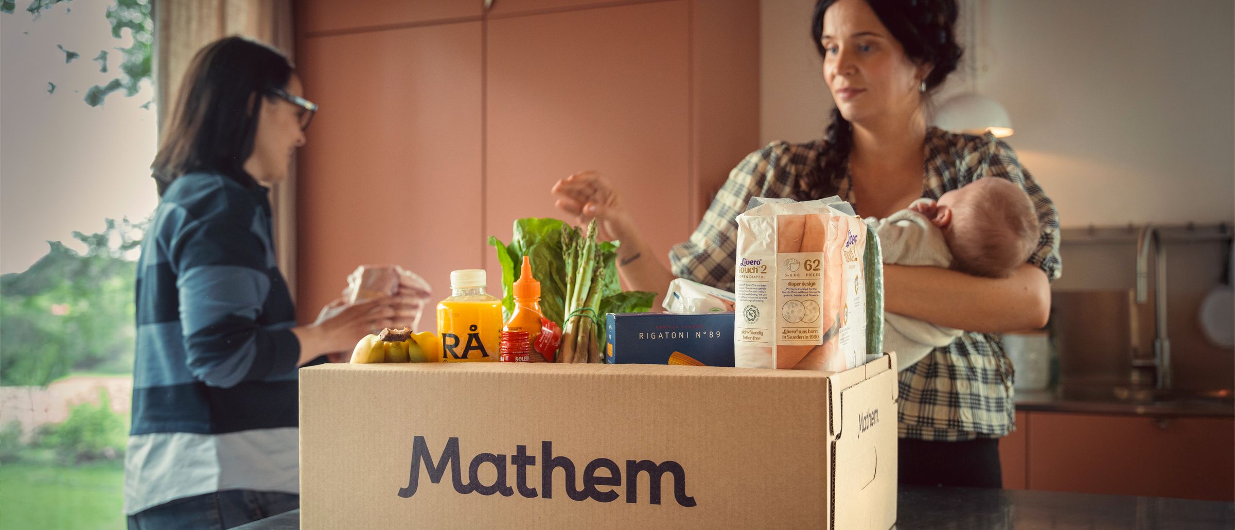 På bilden syns två personer packa ur en Mathem-låda full med varor