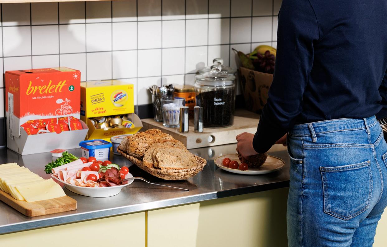 A woman makes lunsj at the office and you can see bread and spreads