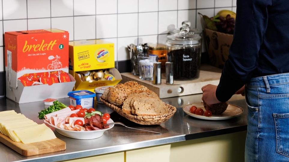 A woman makes lunsj at the office and you can see bread and spreads
