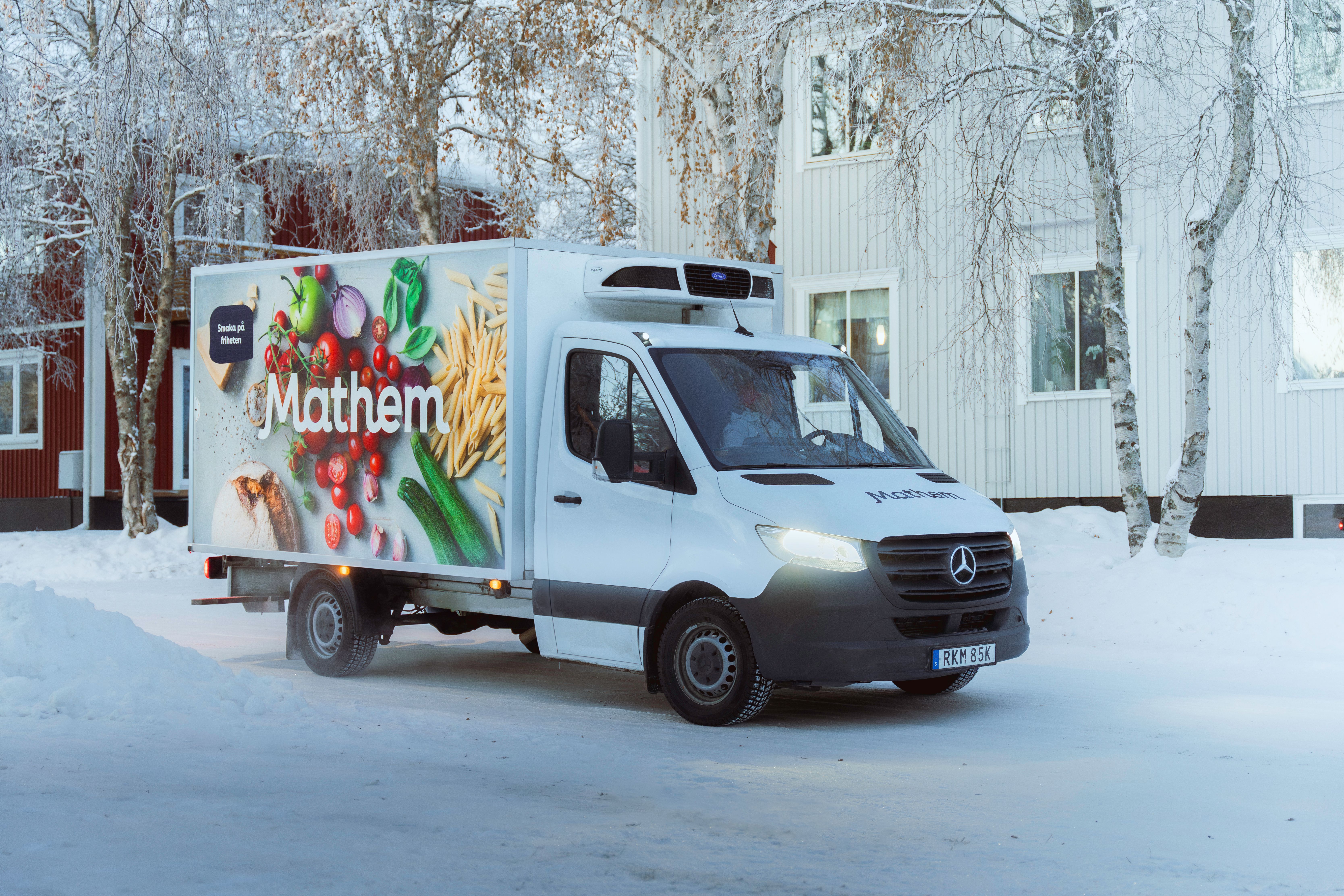 På bilden syns en Mathembil stå utanför ett bostadshus, det är vinter