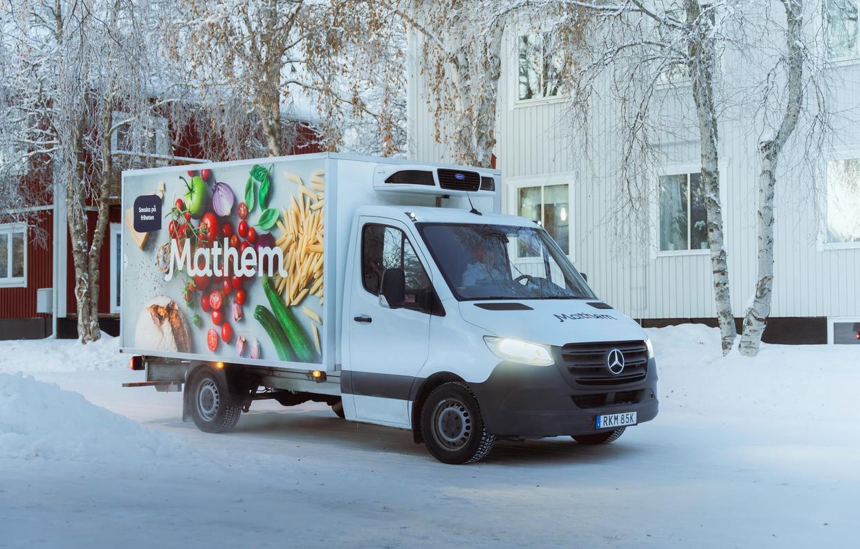 På bilden syns en Mathembil stå utanför ett bostadshus, det är vinter