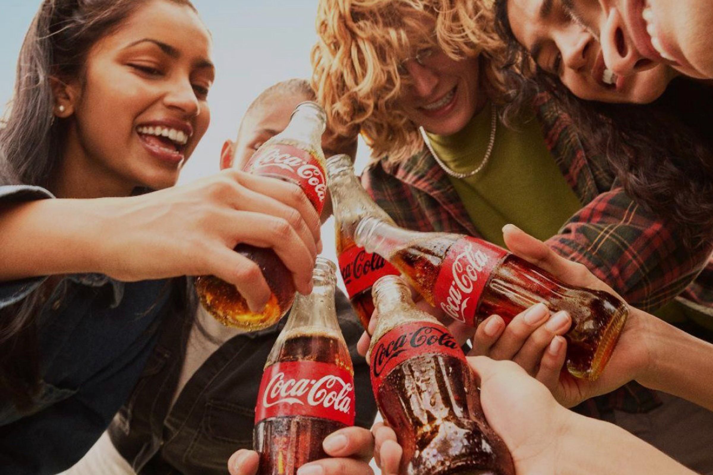 Bildet inneholder flere personer som holder flasker fra Coca-Cola.