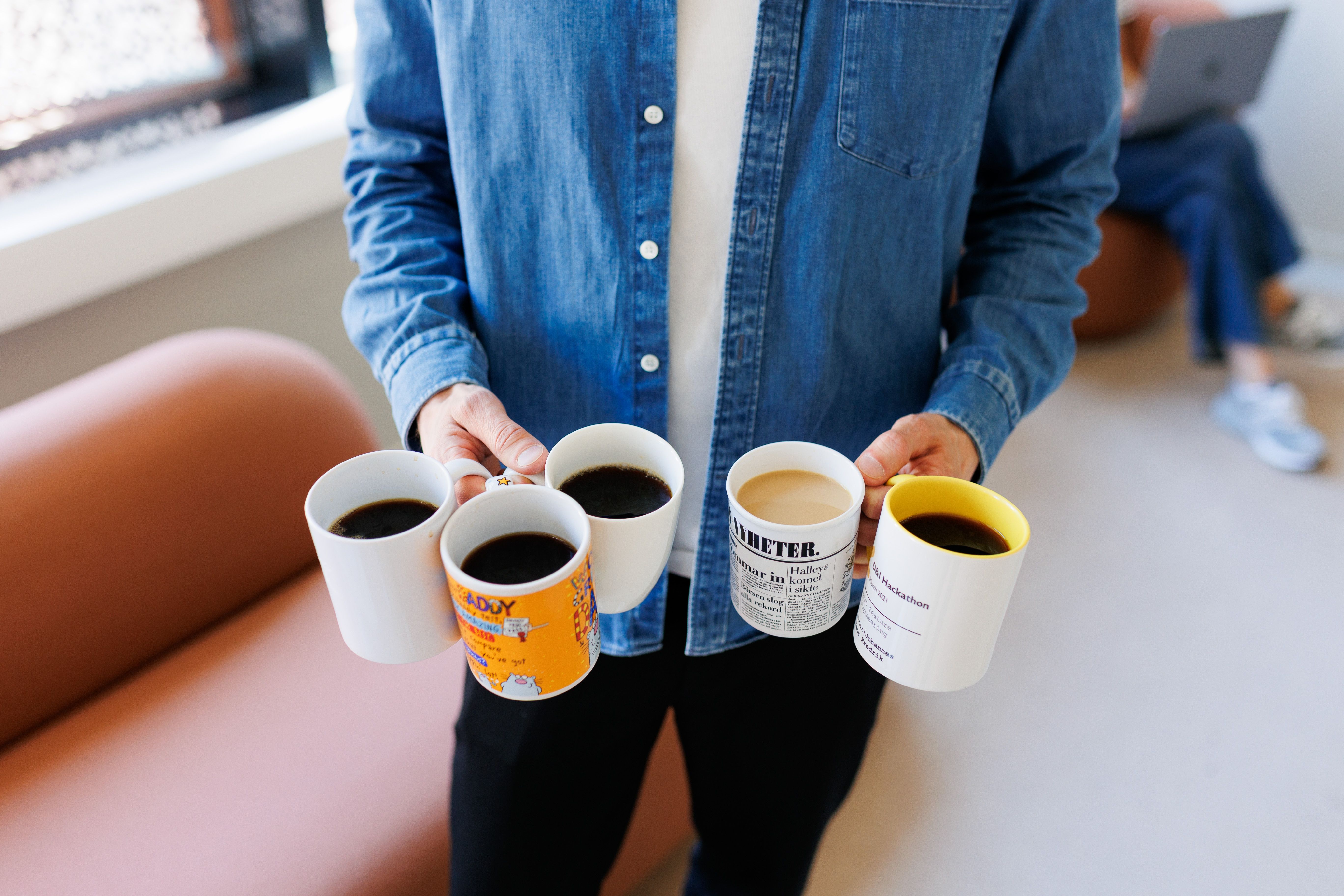 Mann som holder 5 kopper med kaffe
