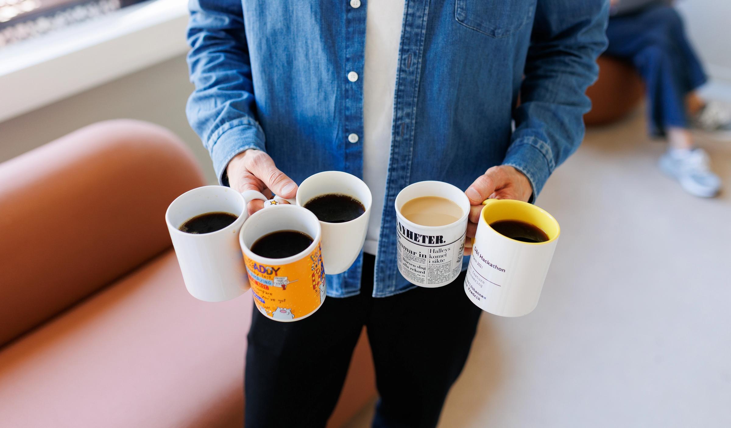 Mann som holder 5 kopper med kaffe