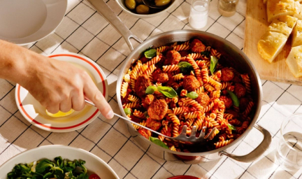 Panne med pasta og kjøttboller, på et bord med rutete klede.