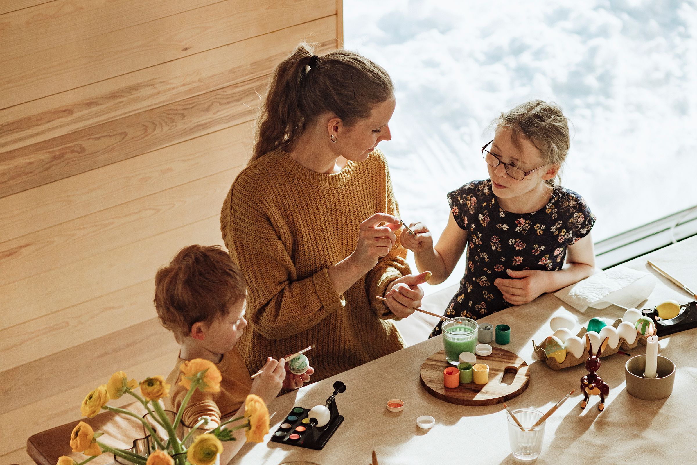 På bildet syns en familie som dekorerer påskeegg