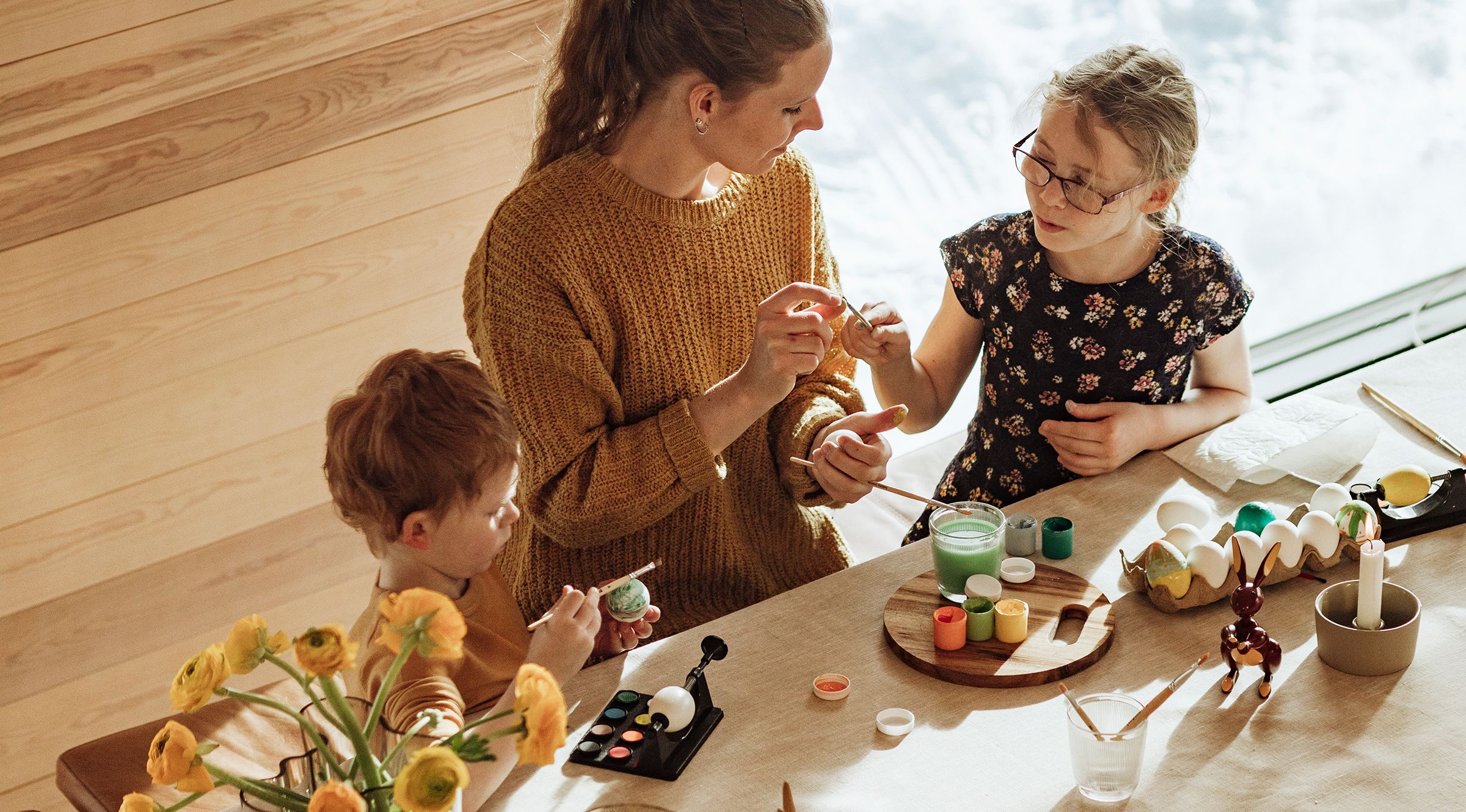 På bildet syns en familie som dekorerer påskeegg