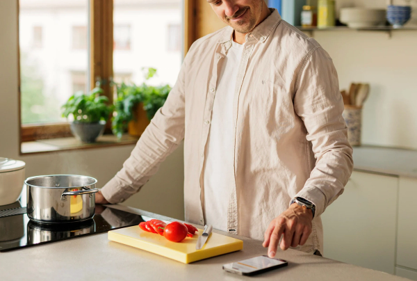 På bildet ser man et barn som står på et kjøkken og ler, det har en agurkskive i pannen.