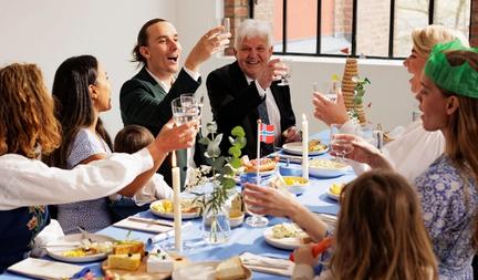 Bildet inneholder en familie som sitter ved bordet og spiser mat på 17. mai.