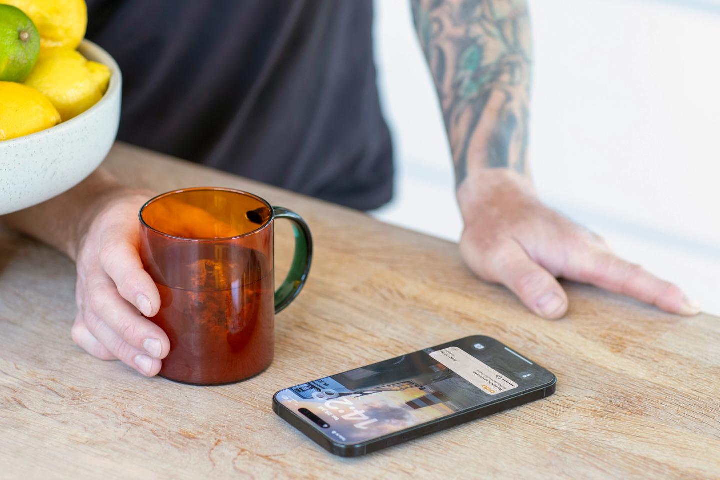 På bildet ser man en telefon og hånd og kaffekopp - hjelp av KI til mobilbakgrunn og blomster ute