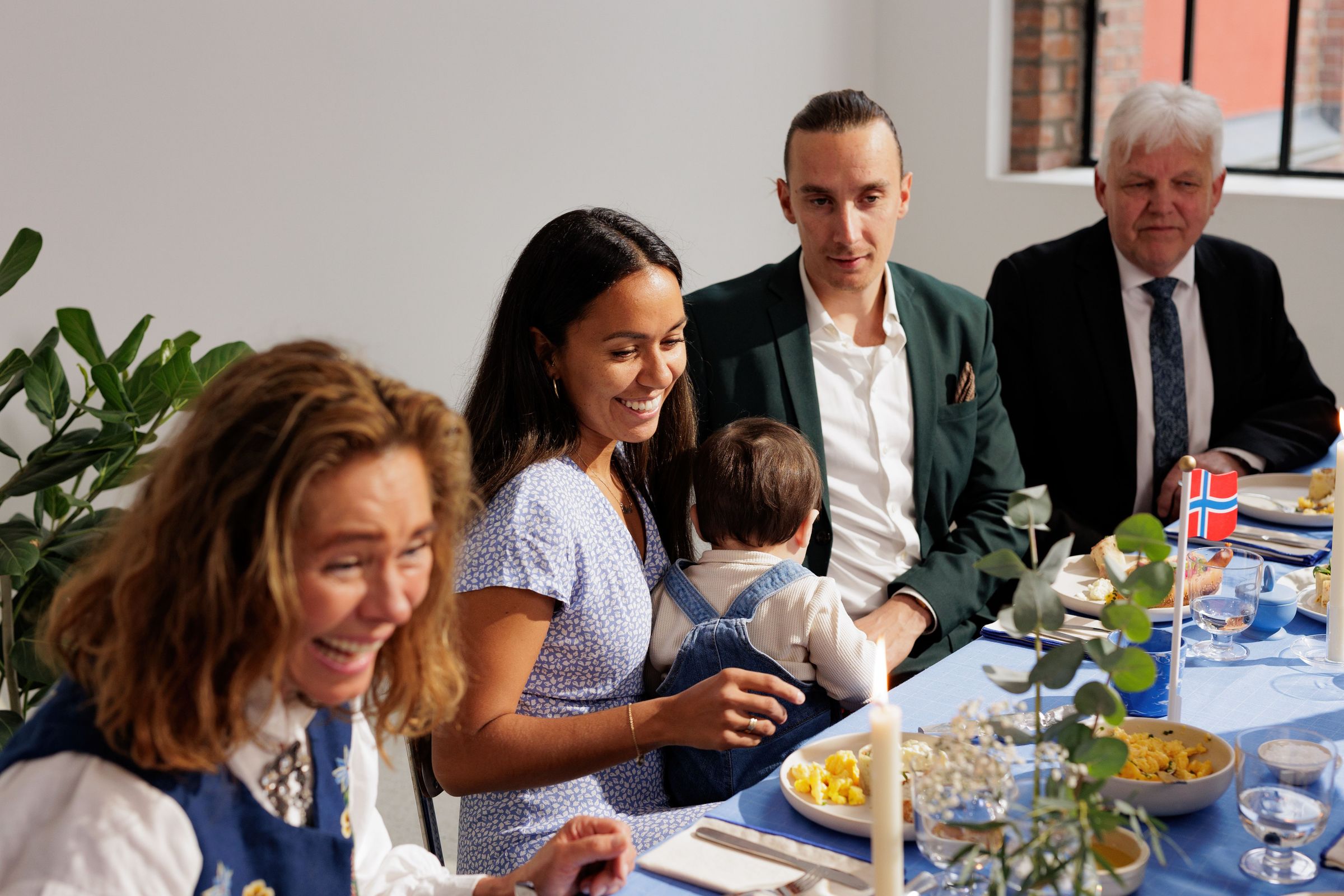 Bildet inneholder en familie som sitter ved bordet og spiser mat på 17. mai.