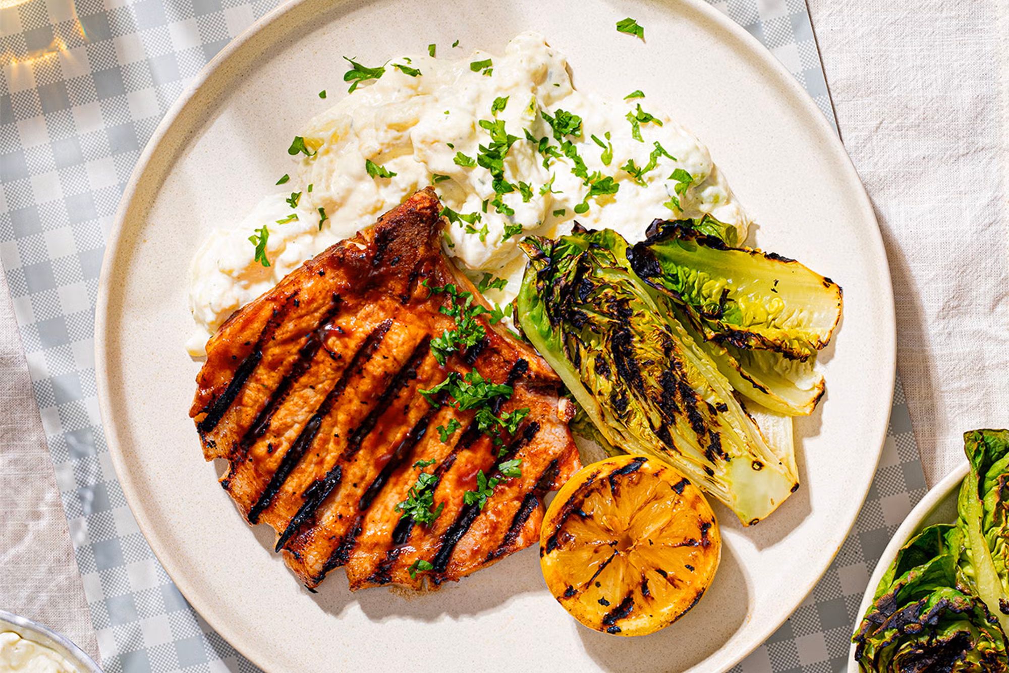 På bildet ser man en tallerken med grillede sommerkoteletter og potetsalat