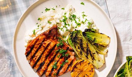 På bildet ser man en tallerken med grillede sommerkoteletter og potetsalat