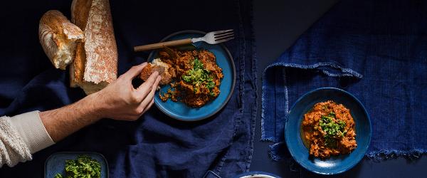 På bilden syns en hand sträcka sig efter en tallrik med högrevsgryta