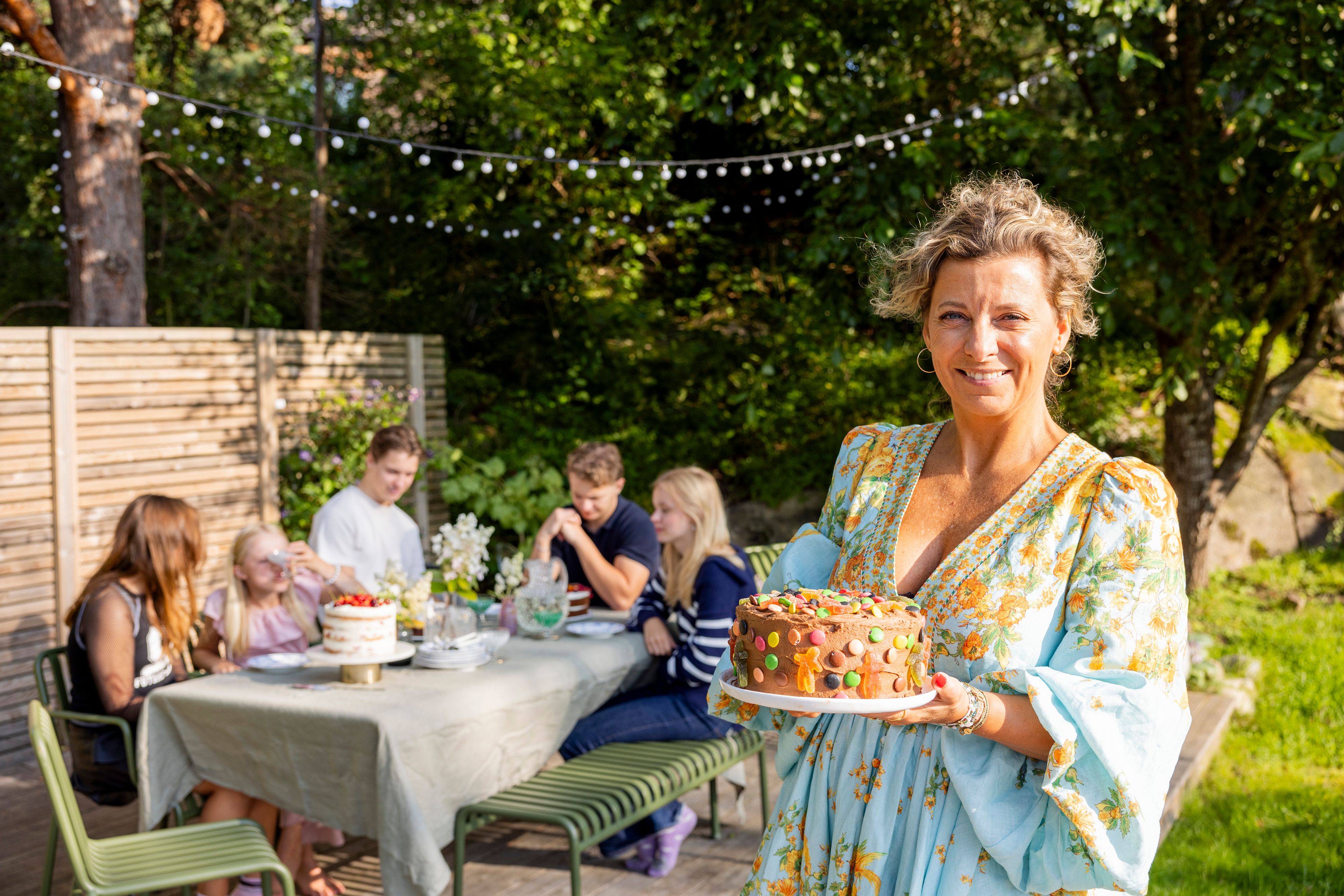 På bildet ser man Lise Finckenhagen holde i en bursdagskake, det er sommer