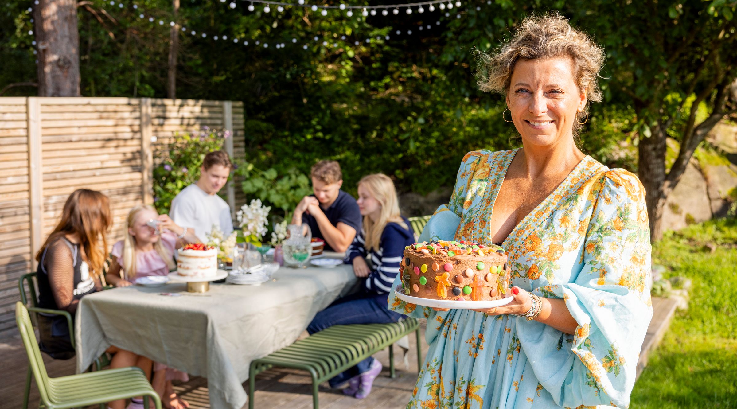På bildet ser man Lise Finckenhagen holde i en bursdagskake, det er sommer