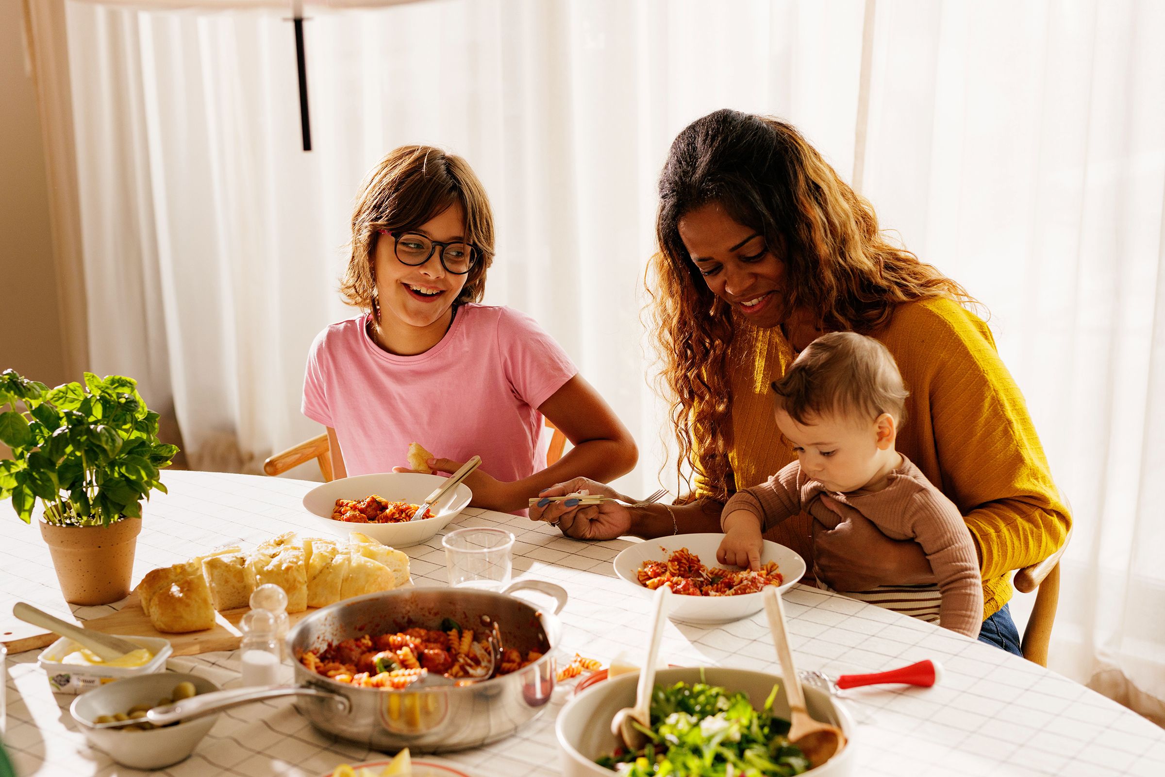Bildet inneholder en familie som sitter ved bordet og spiser mat 