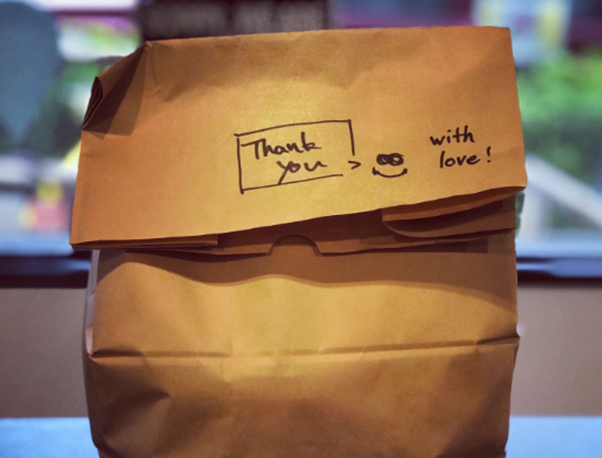 A takeout bag with a handwritten note that reads "Thank you, with love!"