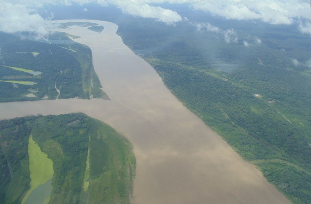 Vista aérea del amplio Amazonas cerca de Iquitos, entre orillas verdes.