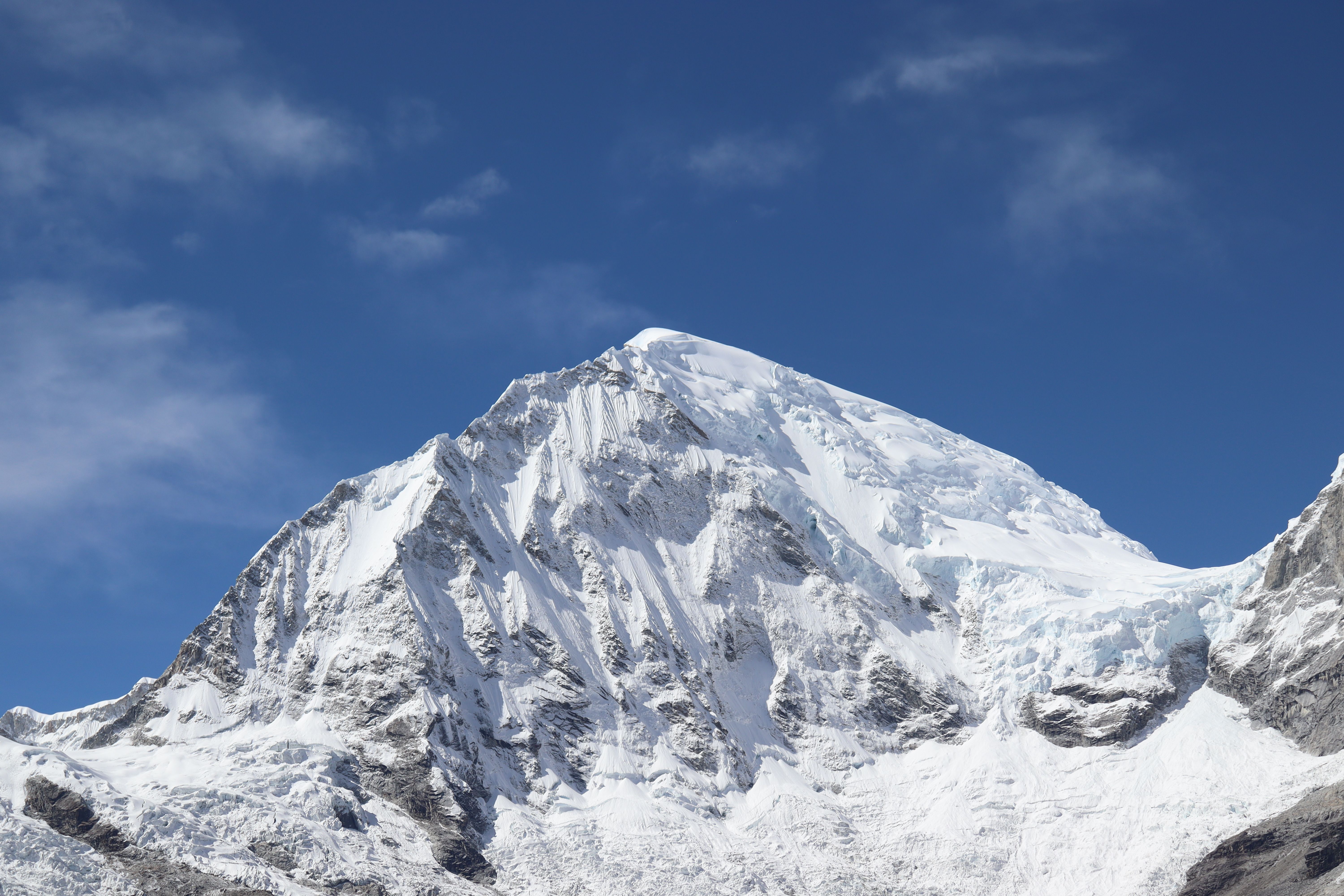 The snow-covered summit and glacier slopes of Huascarán Sur beneath a blue sky.