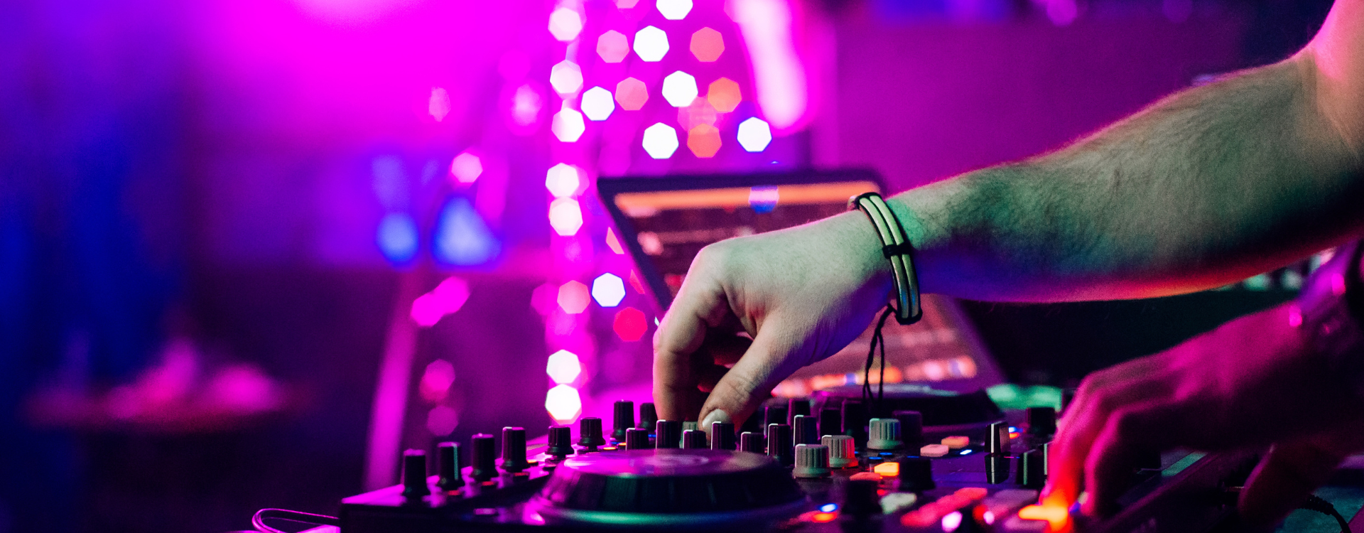 DJ legt auf Hochzeit auf – Mischpult mit bunter Lichtshow im Hintergrund