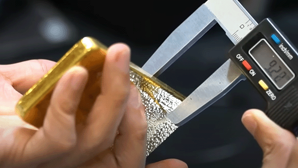 Measuring a gold bar's thickness with a digital caliper