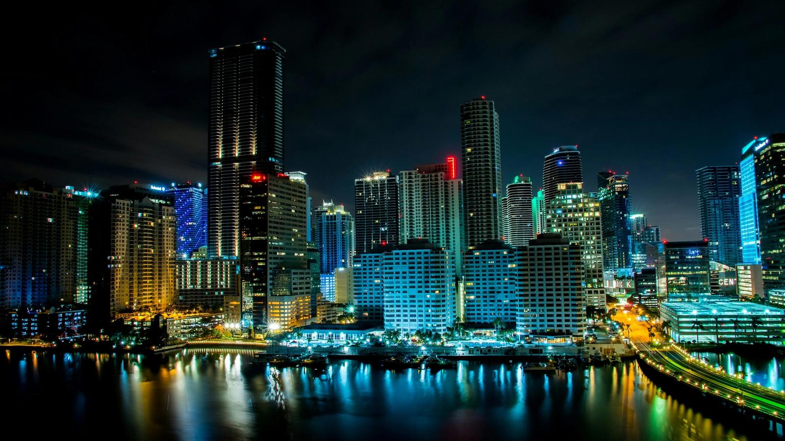 Fotografía real del skyline de Miami iluminado de noche y reflejado sobre Biscayne Bay