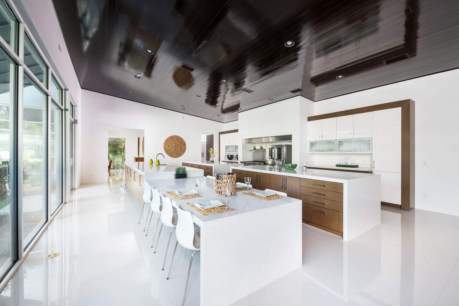 A modern kitchen with white waterfall quartz islands, walnut cabinetry, bar seating, and a professional range