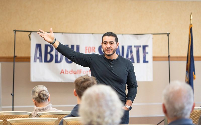 Abdul El-Sayed speaking at a campaign meet-and-greet in front of an "Abdul for US Senate" banner