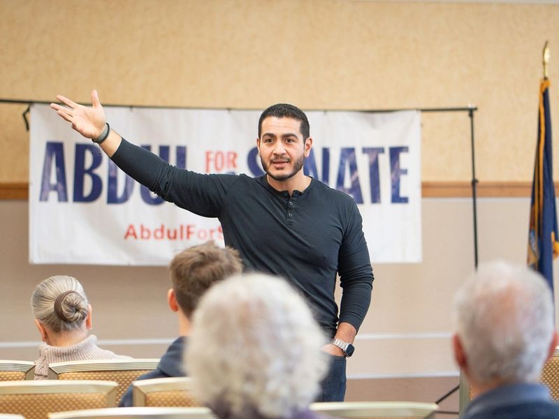 Abdul El-Sayed speaking at a campaign meet-and-greet in front of an "Abdul for US Senate" banner
