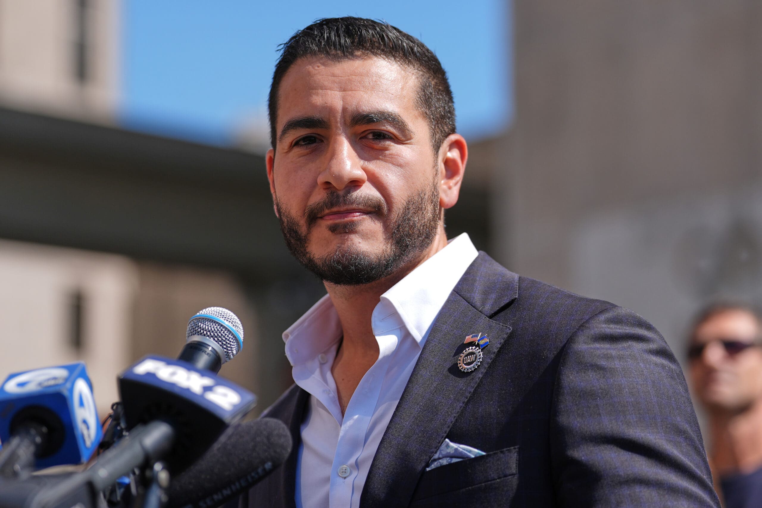 Abdul El-Sayed speaking at a campaign meet-and-greet in front of an "Abdul for US Senate" banner
