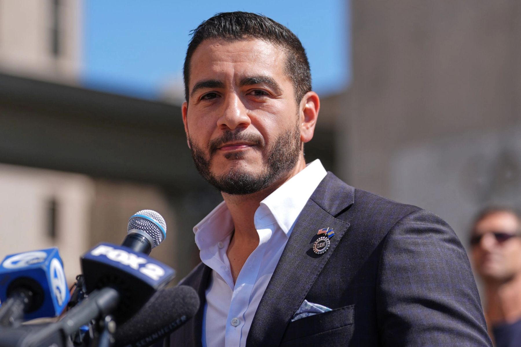 Abdul El-Sayed speaking at a campaign meet-and-greet in front of an "Abdul for US Senate" banner