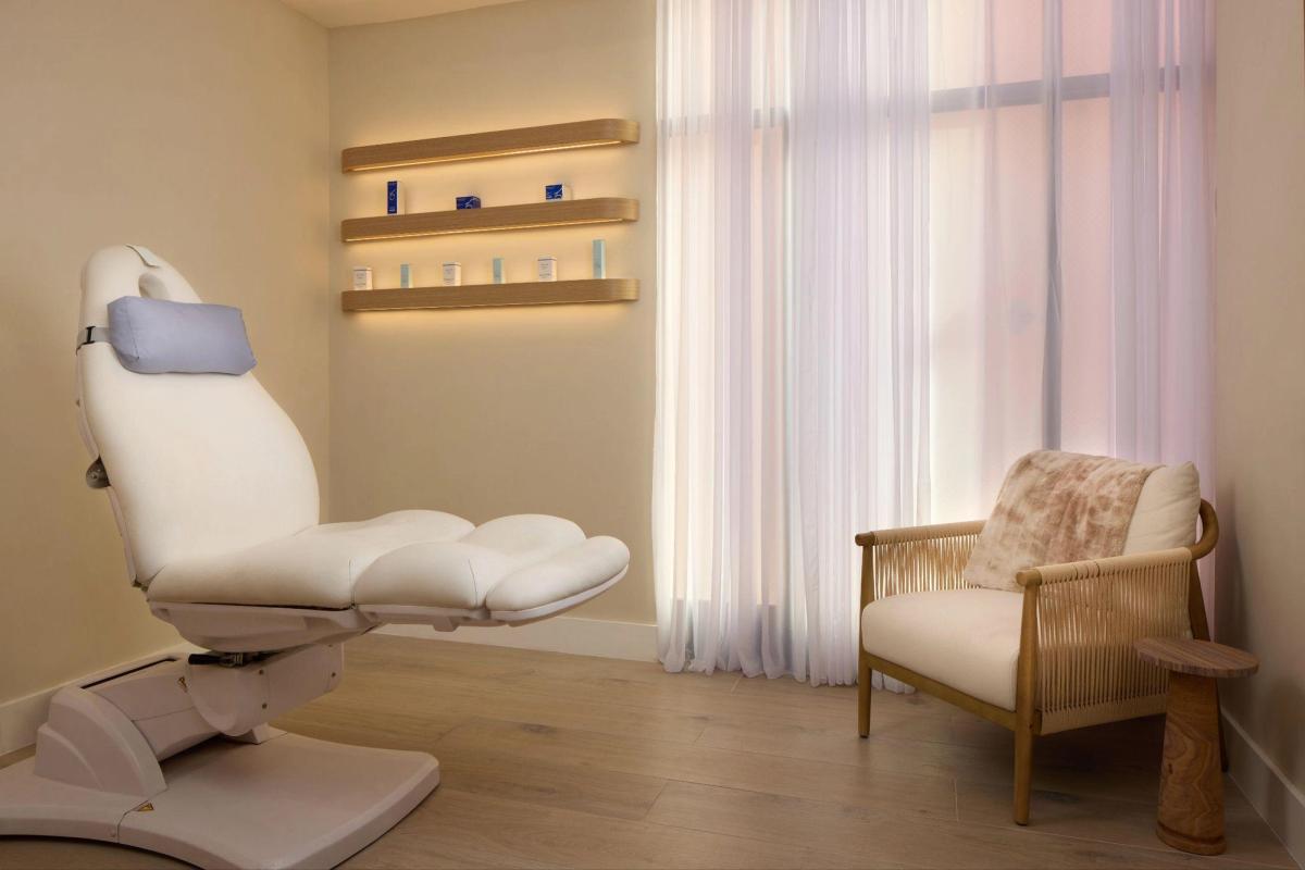 Private treatment room at Cassileth Plastic Surgery in Beverly Hills, with a reclining treatment chair and a seating area by the window.
