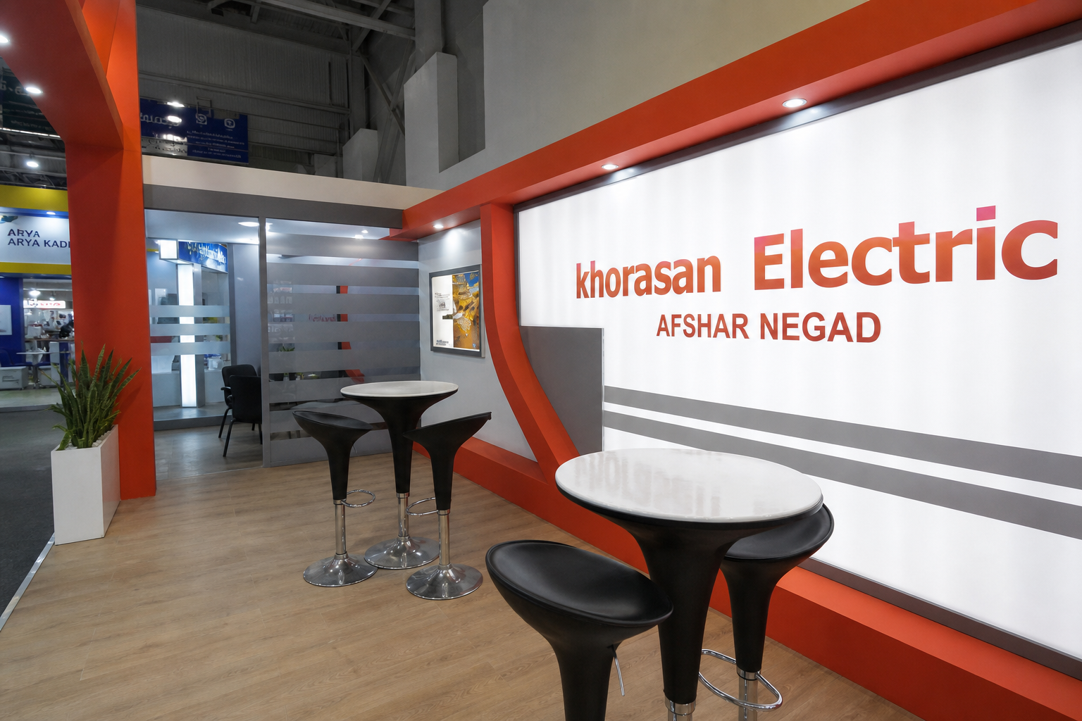 Interior view of the Khorasan Electric exhibition stand with illuminated branding, meeting tables and red structural framing.