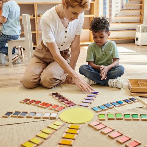 woman and young boy sitting on the floor playing with coloured cards in a play room
