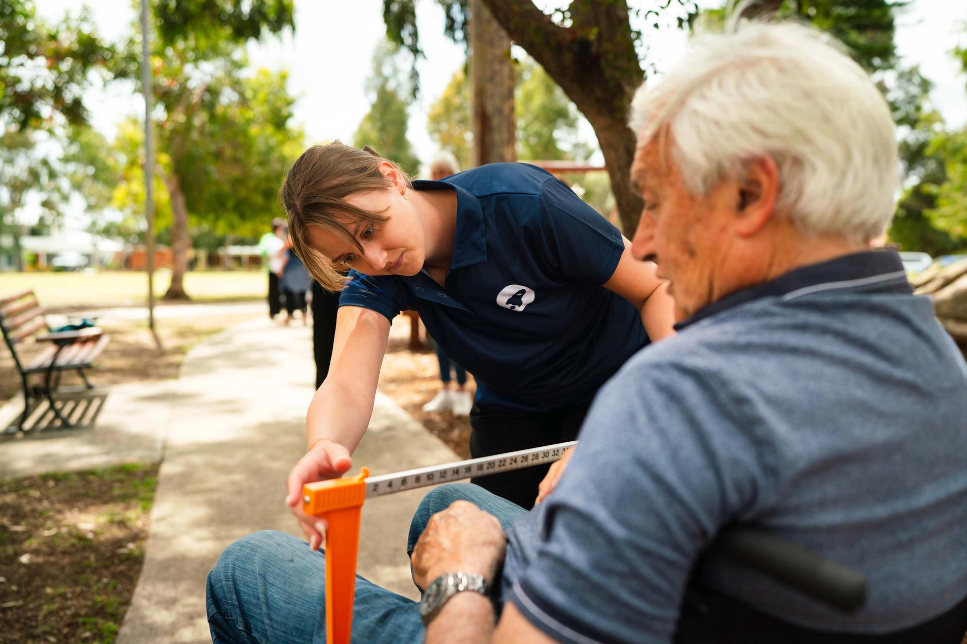 elderly man getting measured up by a BlueRocket clinician in a wheelchair