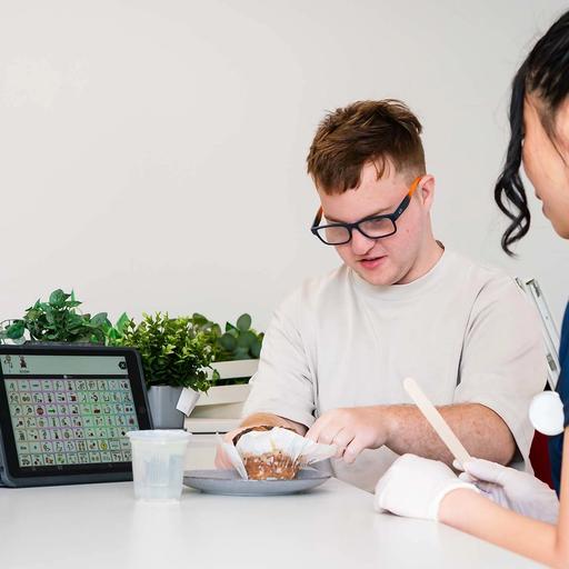 A young man unwrapping a muffin sitting with BlueRocket clinician
