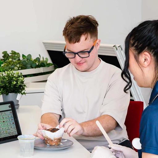 Teenage boy unwrapping a muffin, sitting with BlueRocket clinician