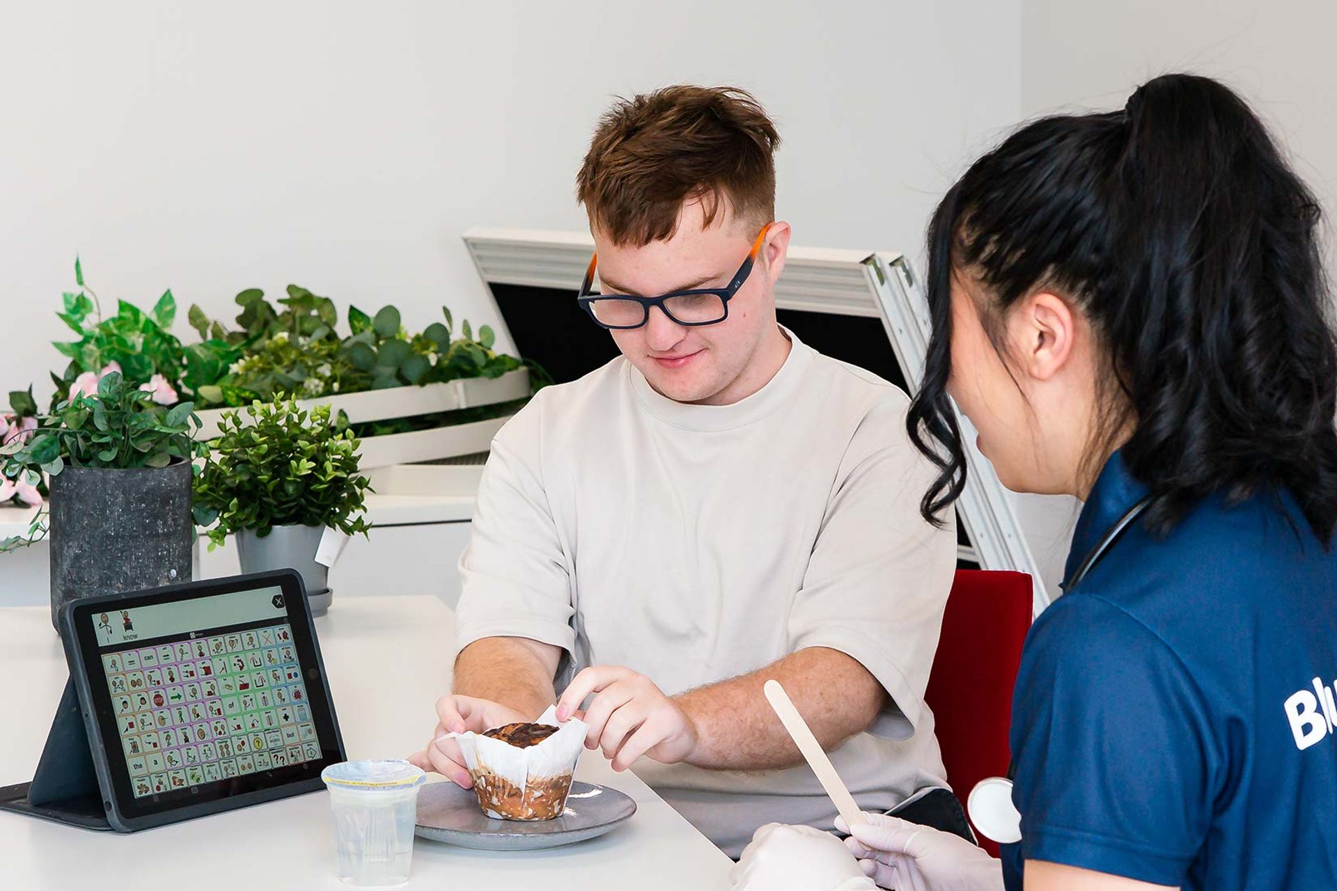 Teenage boy unwrapping a muffin, sitting with BlueRocket clinician