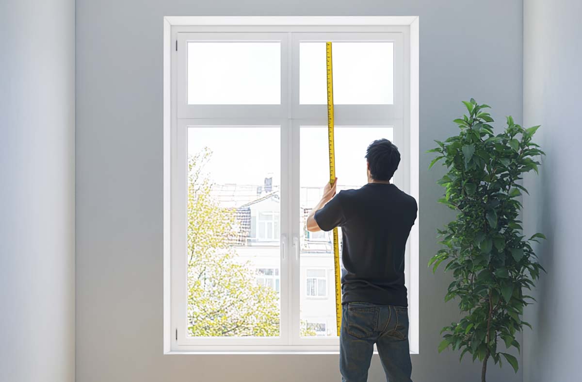 person measuring a window for curtains