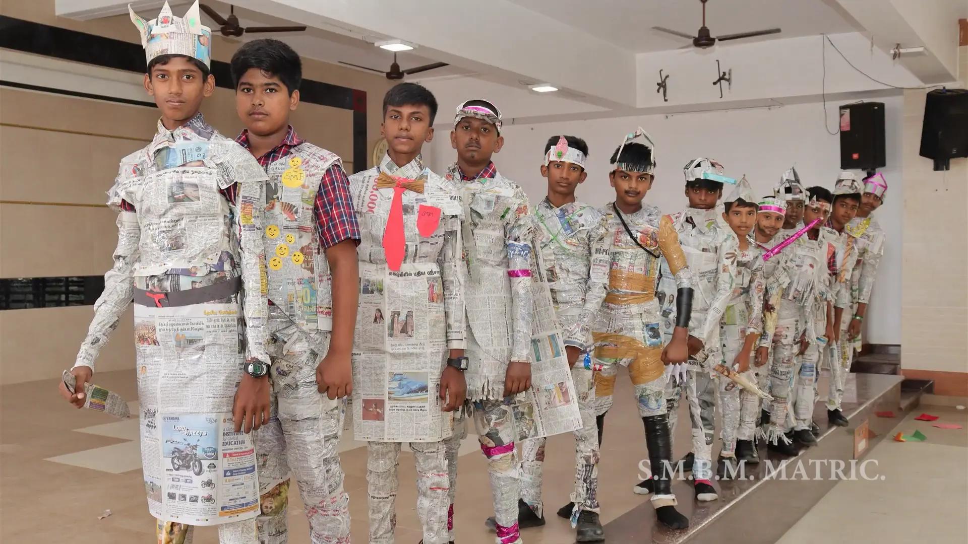 Group of students modeling creative dresses made from recycled paper.