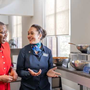 Een reiziger praat met een medewerker in een lounge.