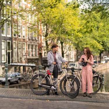 Two friends looking at directions on a bridge in Amsterdam