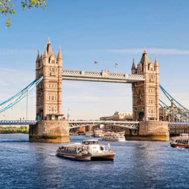 Thames river cruises passing under Tower Bridge on a sunny summer day.